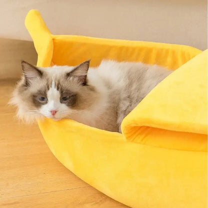 Ragdoll cat lounging inside a bright yellow banana-shaped pet bed.