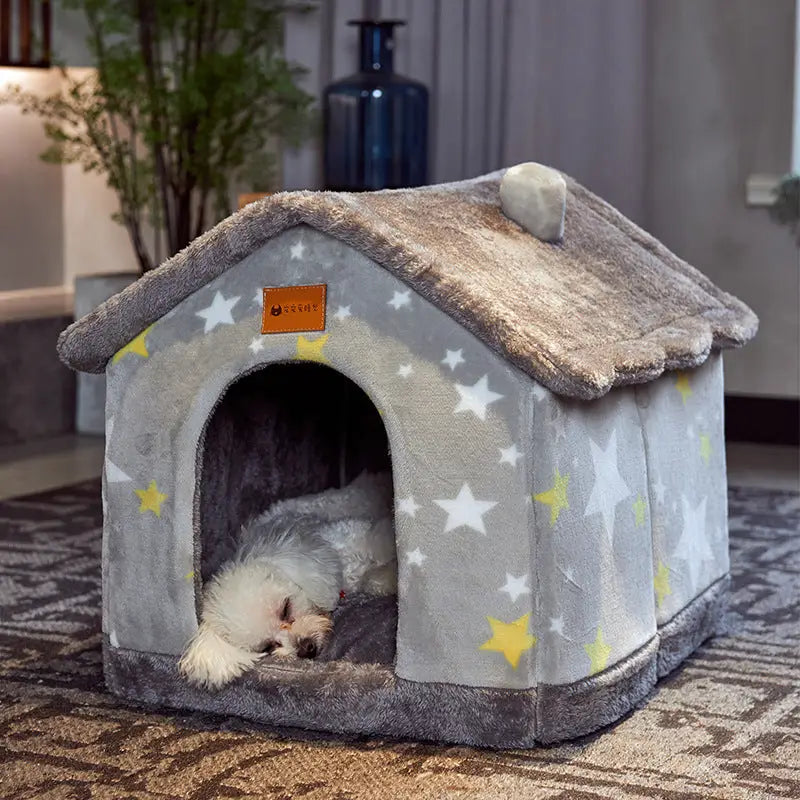 A gray pet house decorated with white and yellow stars and a plush roof with a small white dog resting inside.