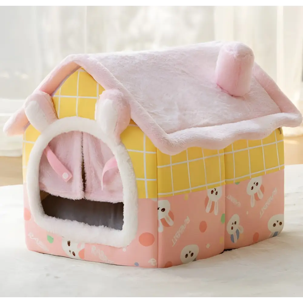 Pink and yellow plush pet house with ghost pattern decorations.