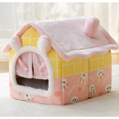 Pink and yellow plush pet house with ghost pattern decorations.